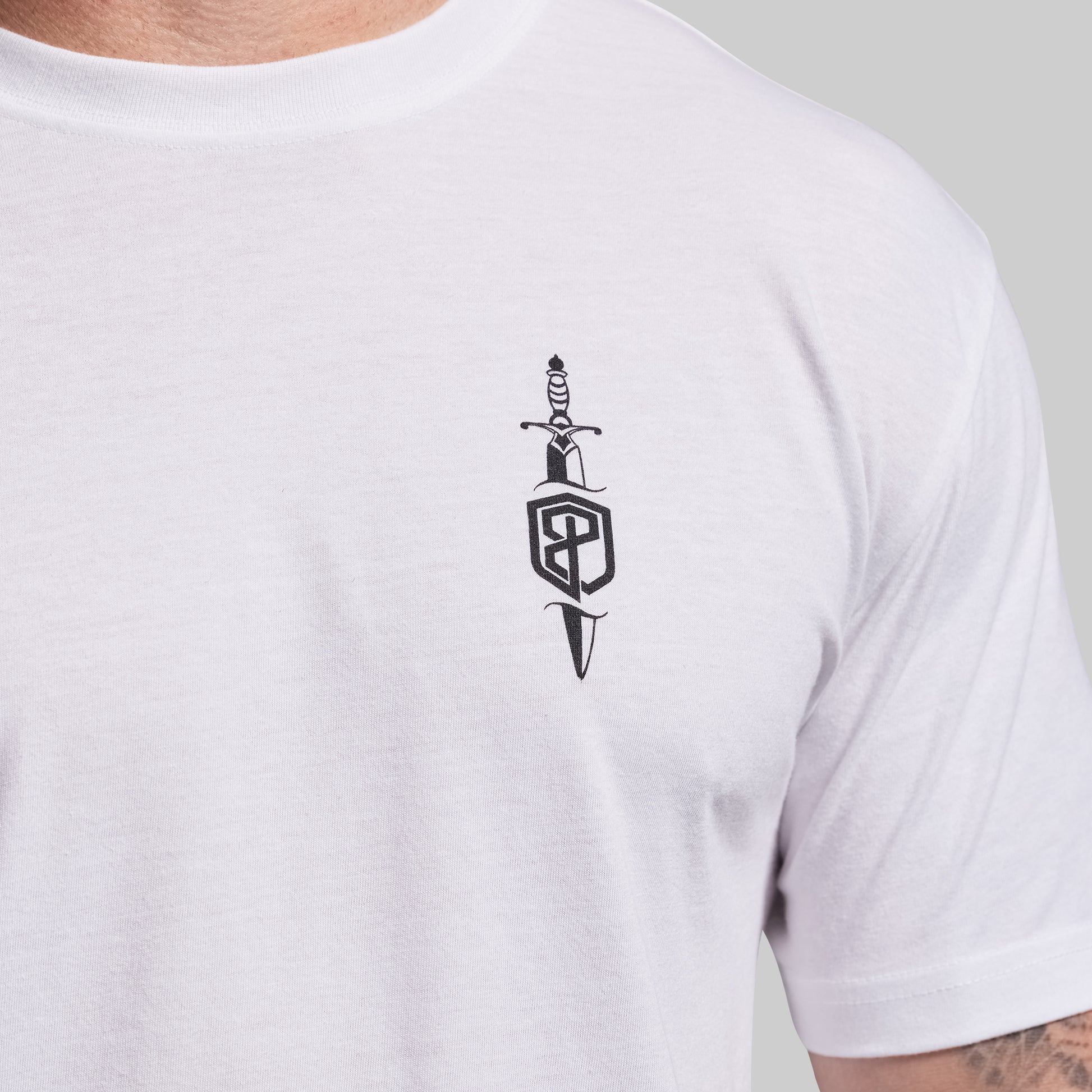 White t-shirt with a black dagger and shield logo on a plain background