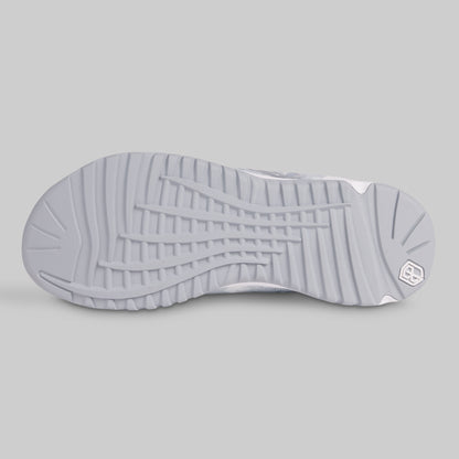 Close-up of a gray sneaker sole with a brand logo on a light gray background