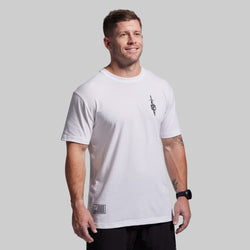 Man wearing a white t-shirt with a small logo on a gray background