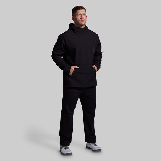 Man wearing a black hoodie and pants on a light gray background