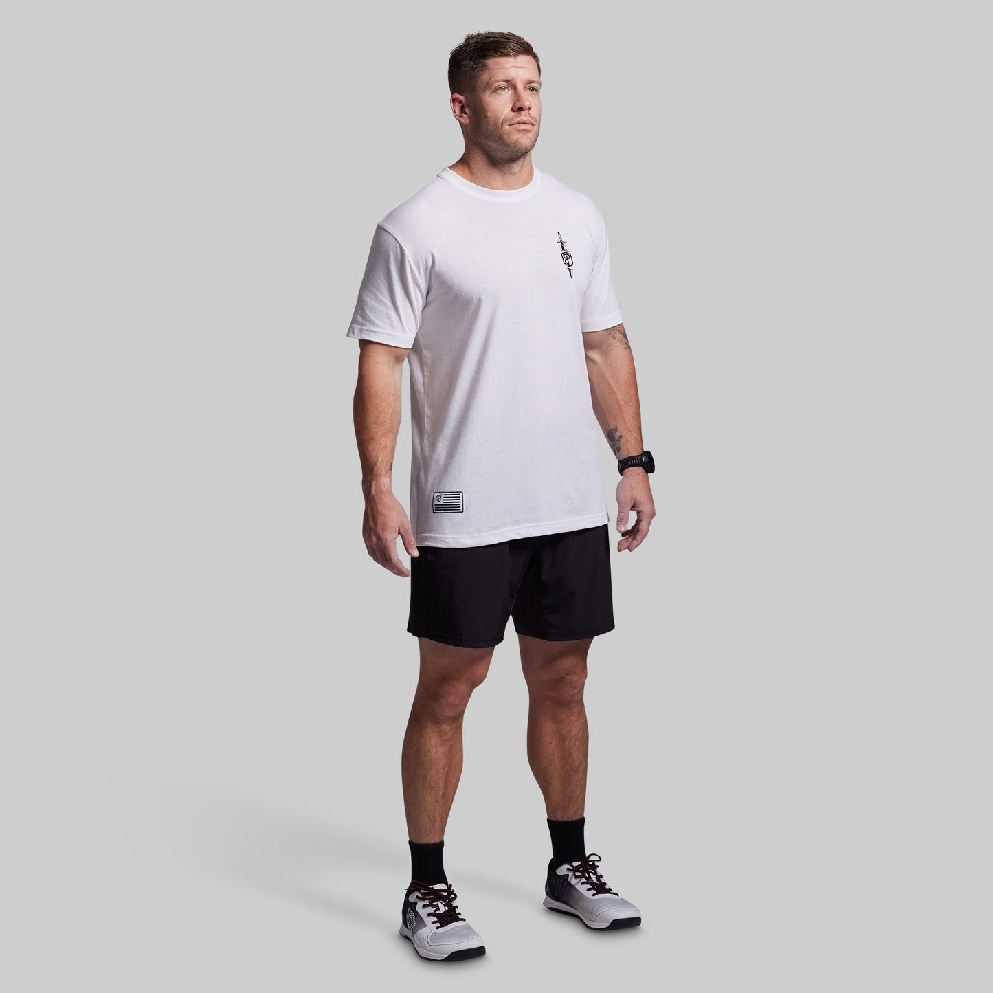 Man wearing a white t-shirt and black shorts on a gray background