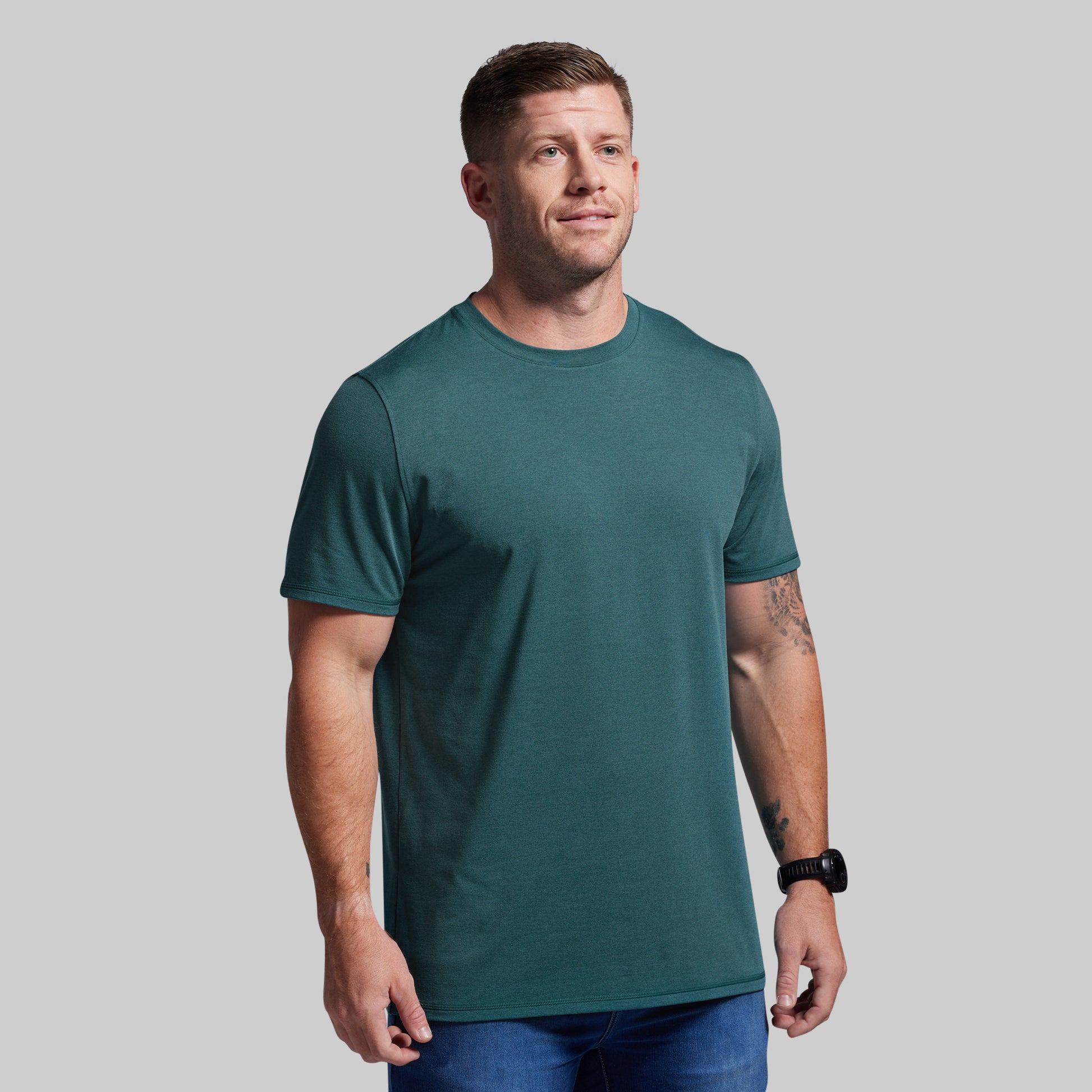 Man wearing a teal t-shirt against a gray background