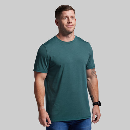 Man wearing a teal t-shirt against a gray background