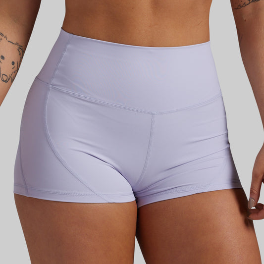 Close-up of a model wearing high-waisted athletic shorts in a light lavender purple color, showing the waistband and hip contours against a solid gray background.