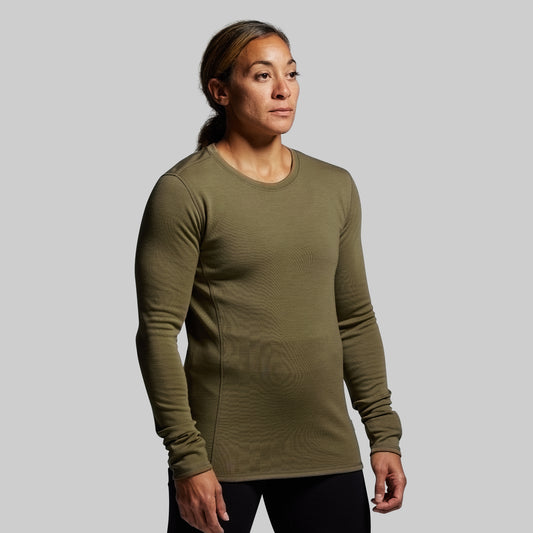 Person wearing a green long-sleeve shirt against a gray background