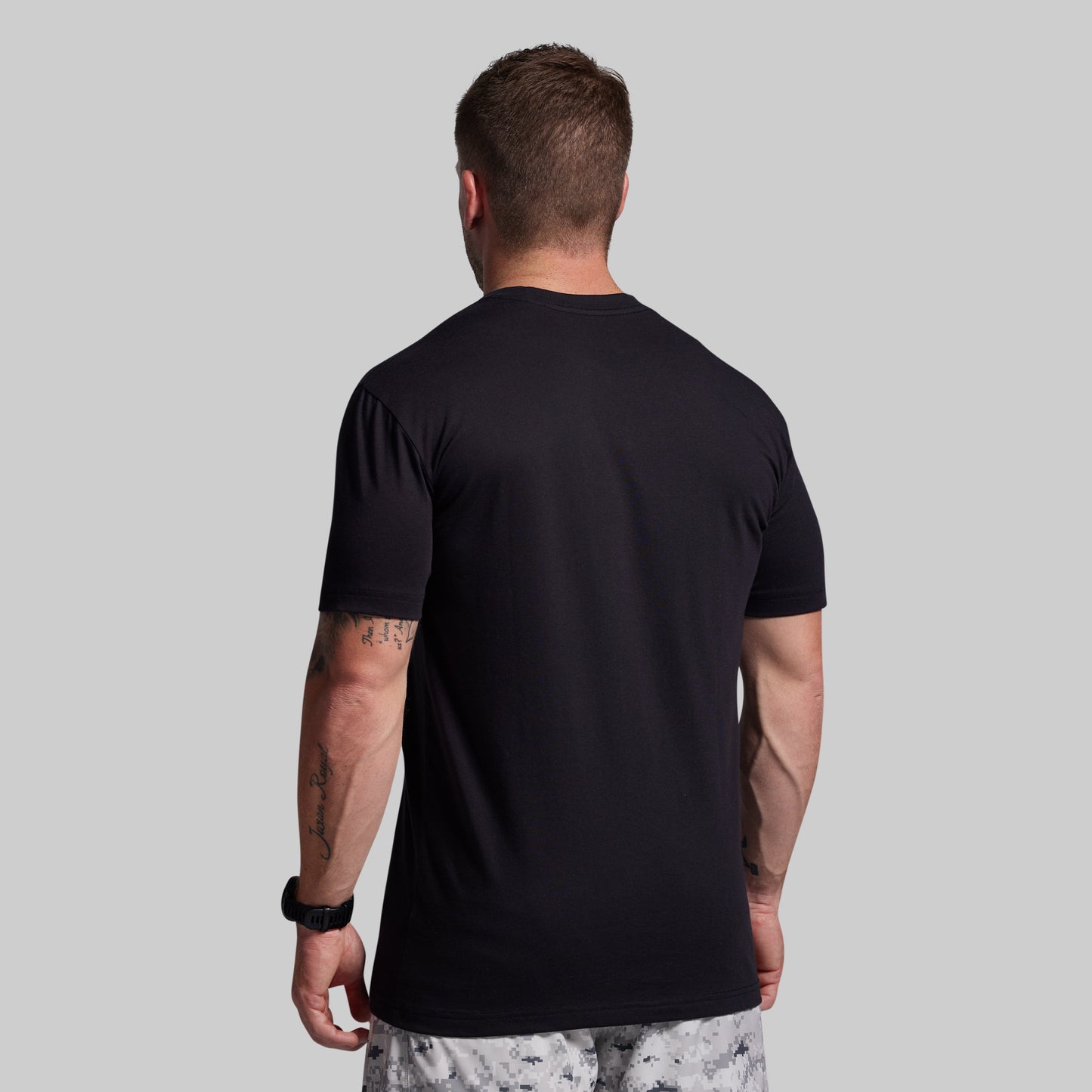 Man wearing a black t-shirt against a gray background
