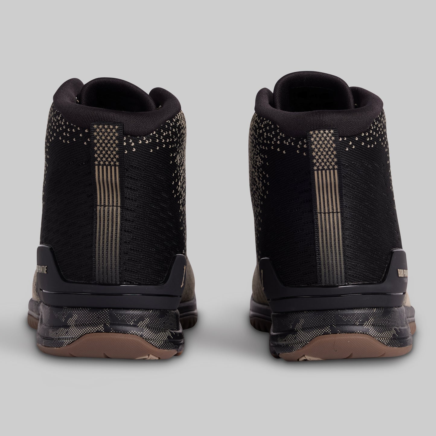Black high-top sneakers with decorative elements on a light gray background