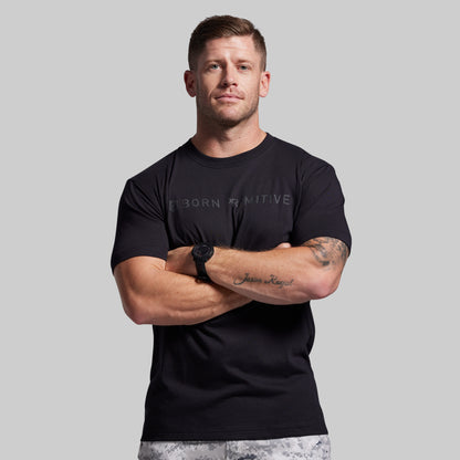 Man wearing a black t-shirt with visible branding against a gray background