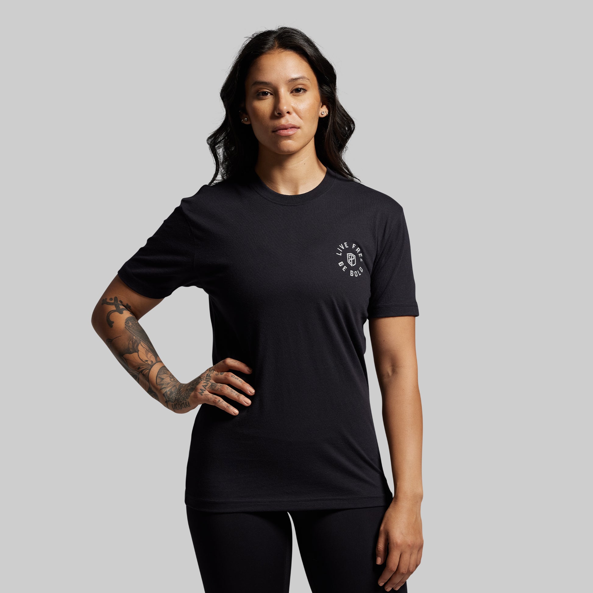 Person wearing a black t-shirt with a logo on a gray background