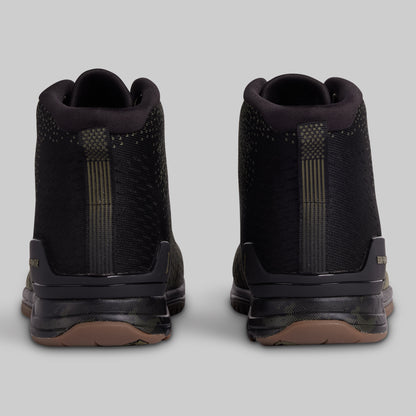 Black high-top sneakers with brown soles on a light gray background