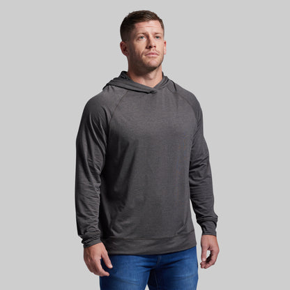 Man wearing a gray hoodie and blue jeans against a plain background