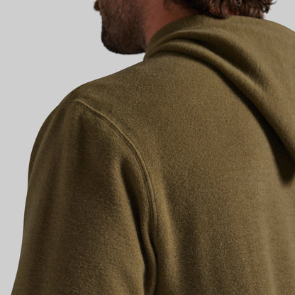 Close-up of a man wearing an olive green hooded sweatshirt, focusing on the back of the neck, shoulder seam, and textured fabric against a plain light gray background.