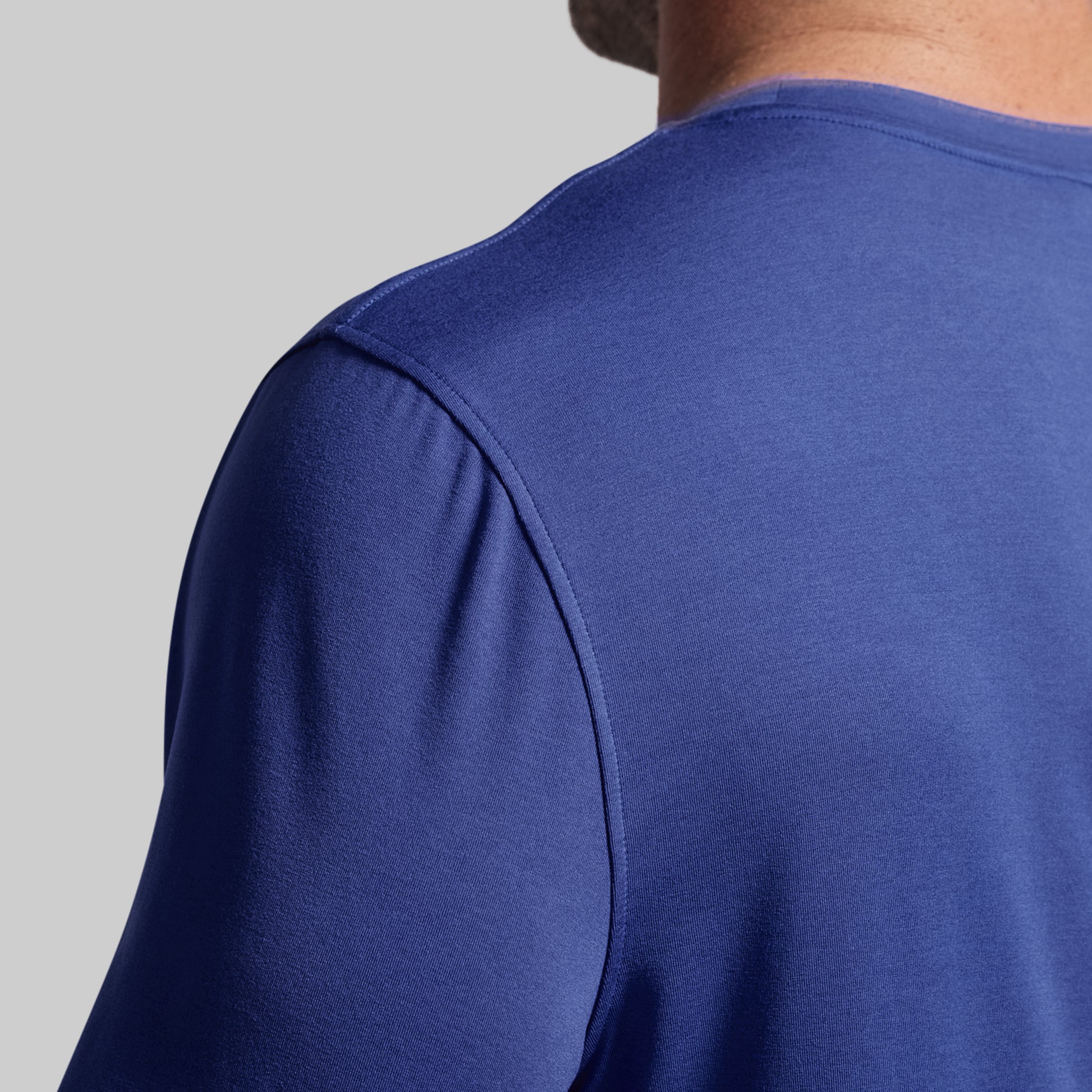 Close-up of a person wearing a blue long-sleeve shirt on a gray background