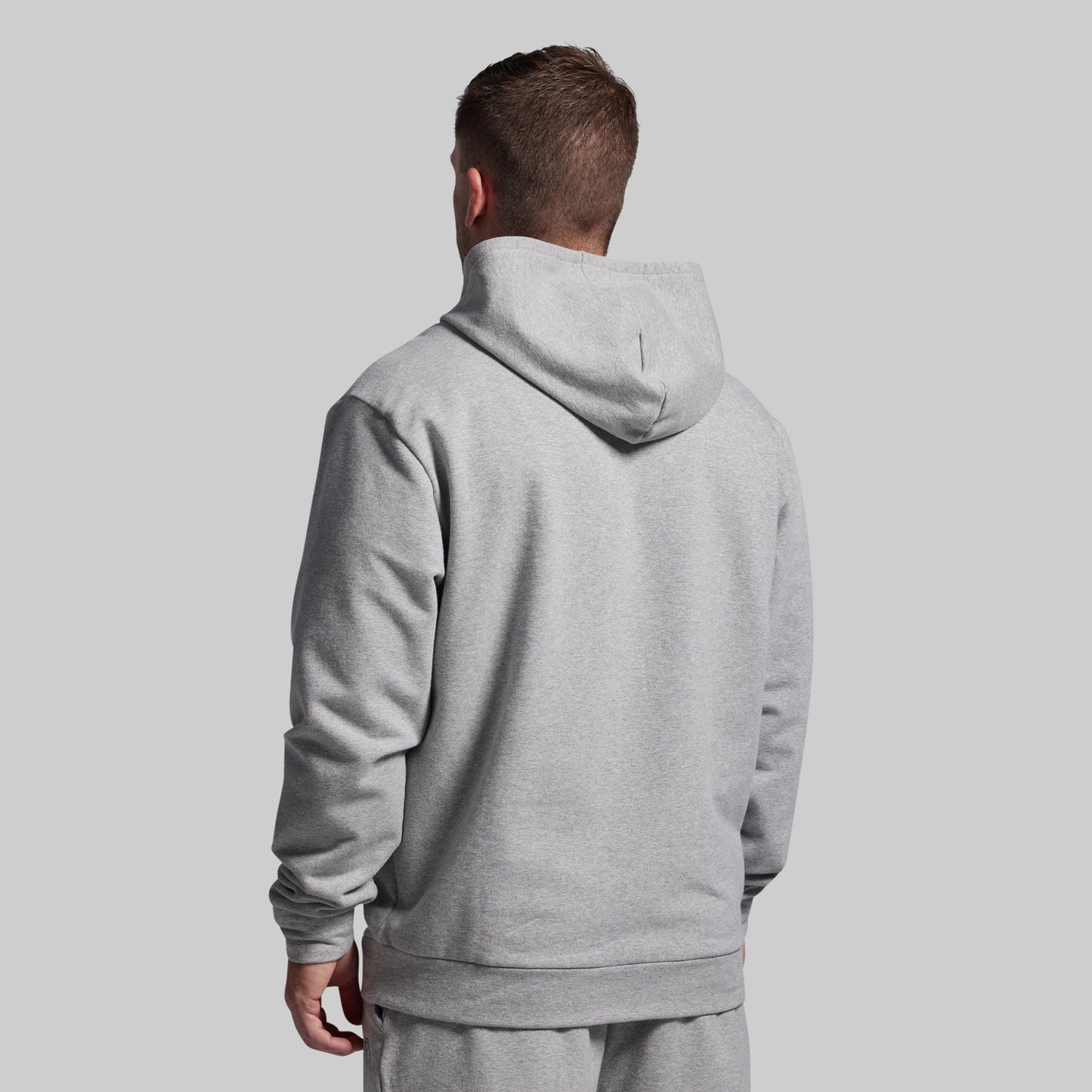 Person wearing a gray hoodie from behind on a light gray background