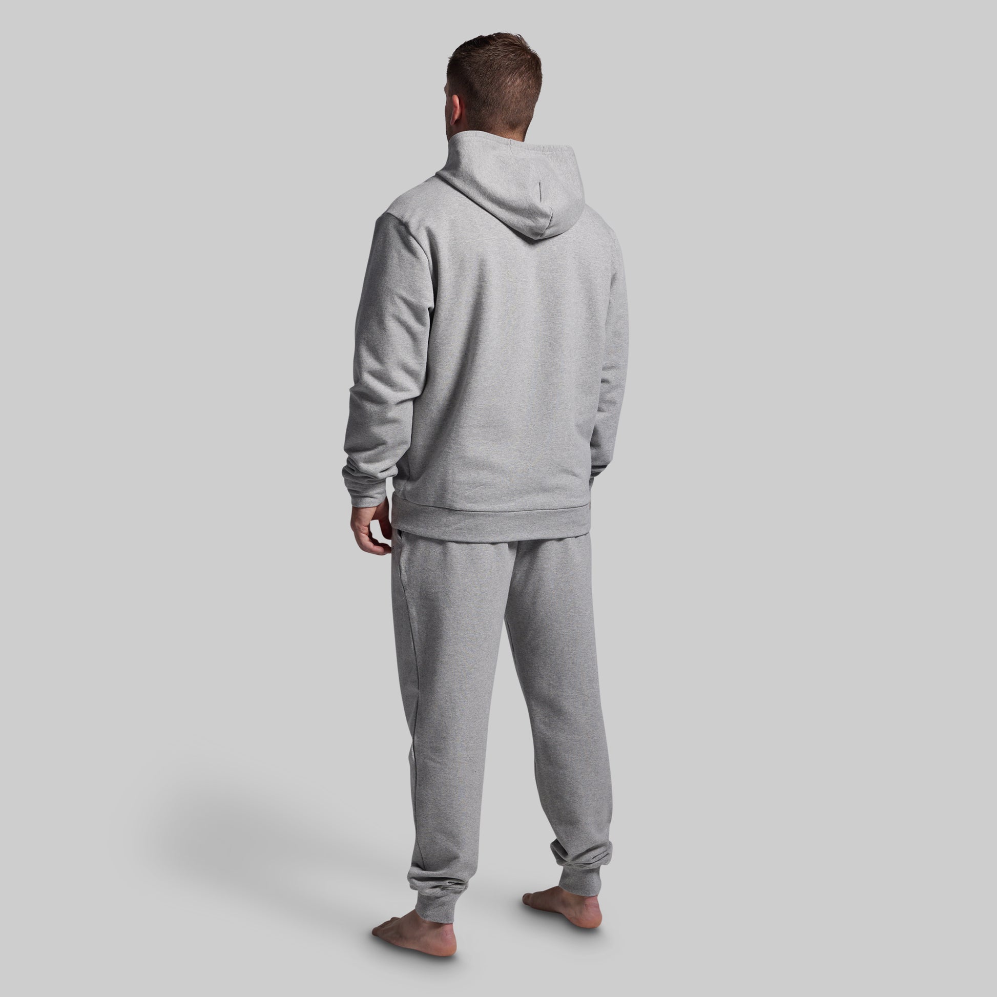 Person wearing a gray tracksuit against a plain background
