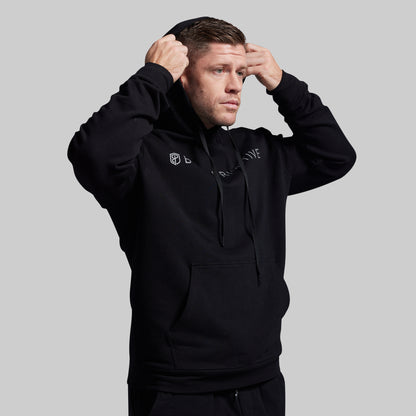 Man wearing a black hoodie with branding on a gray background
