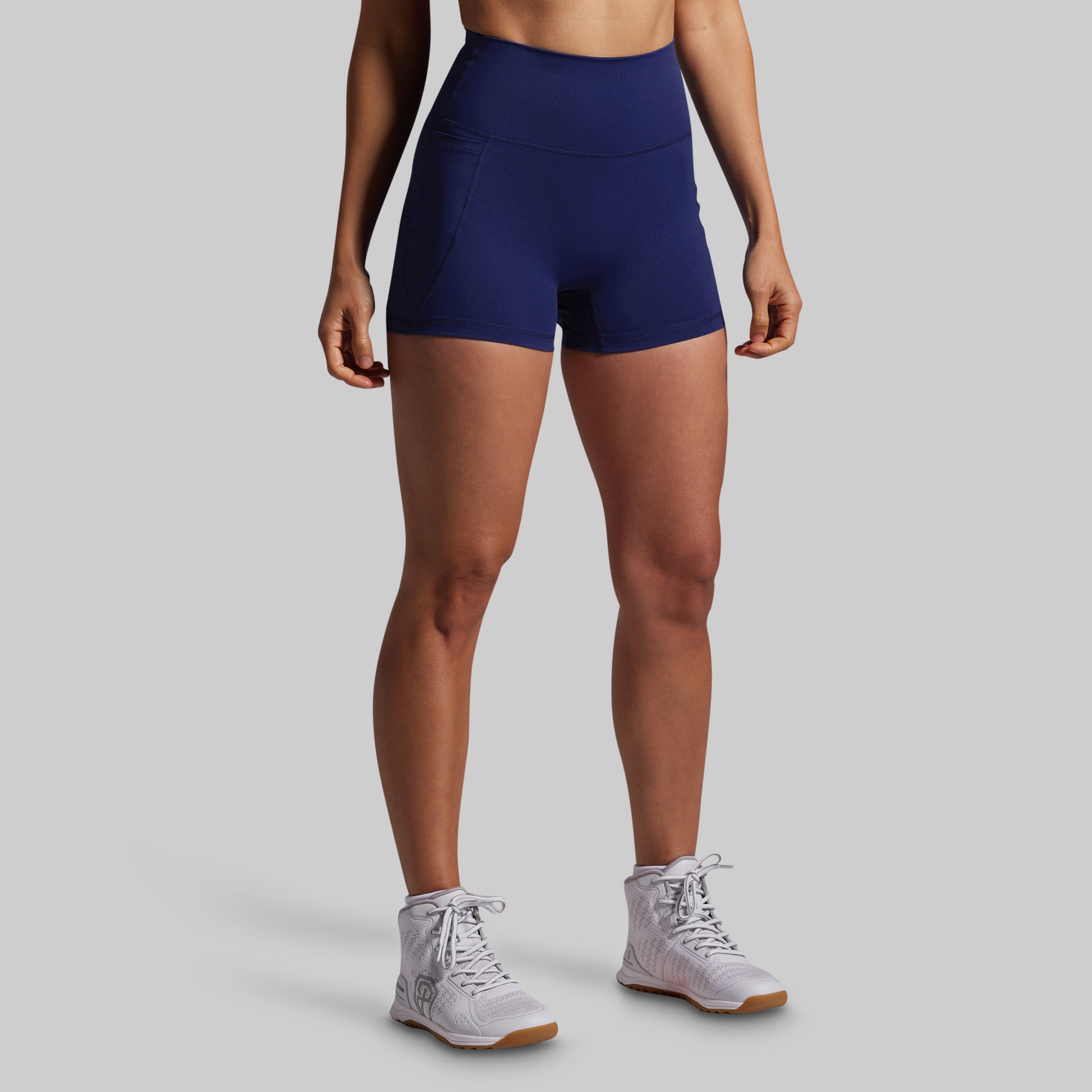 Person wearing navy blue athletic shorts on a gray background