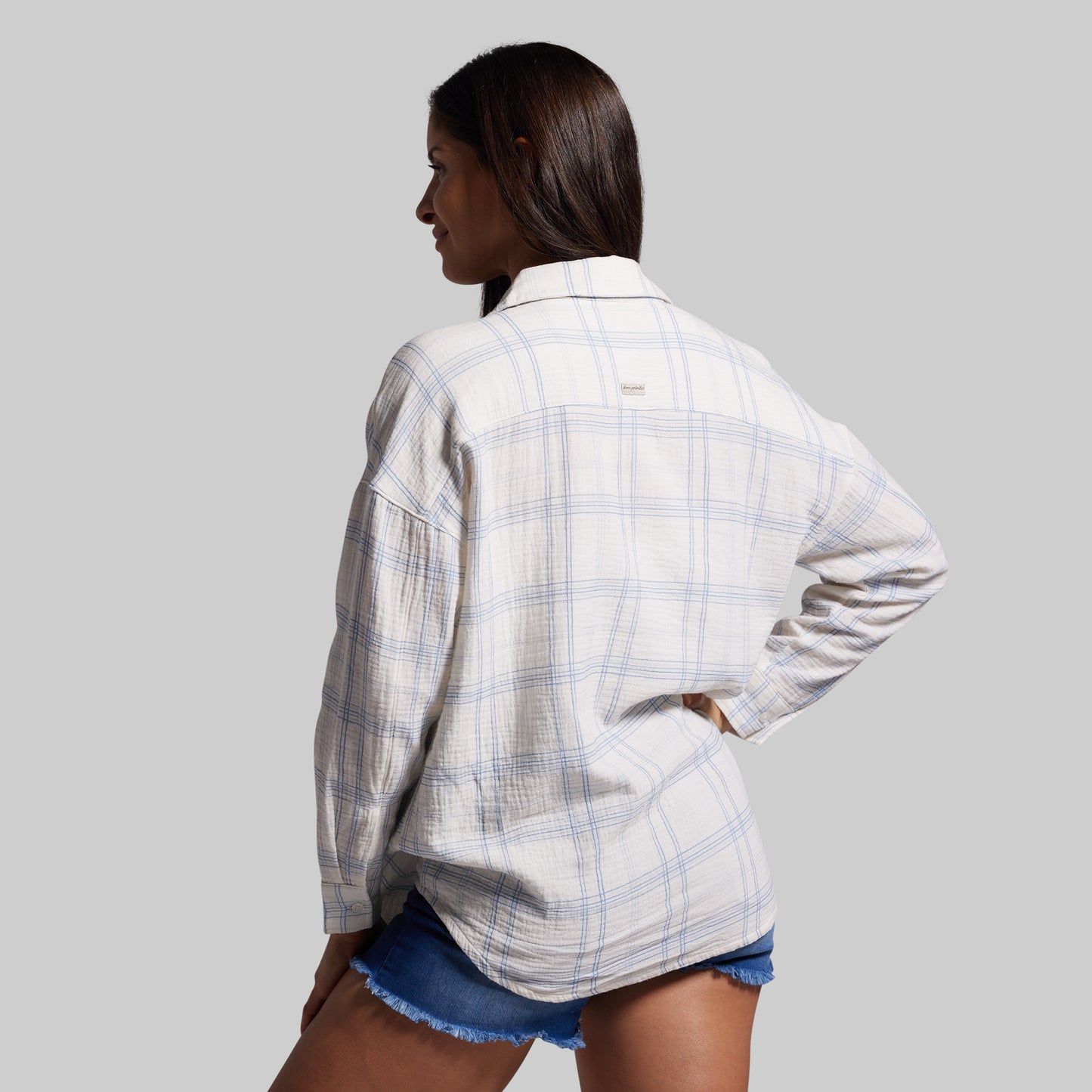 Person wearing a plaid shirt and denim shorts on a gray background