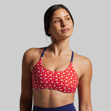 Woman wearing a red sports bra with white star pattern on a gray background