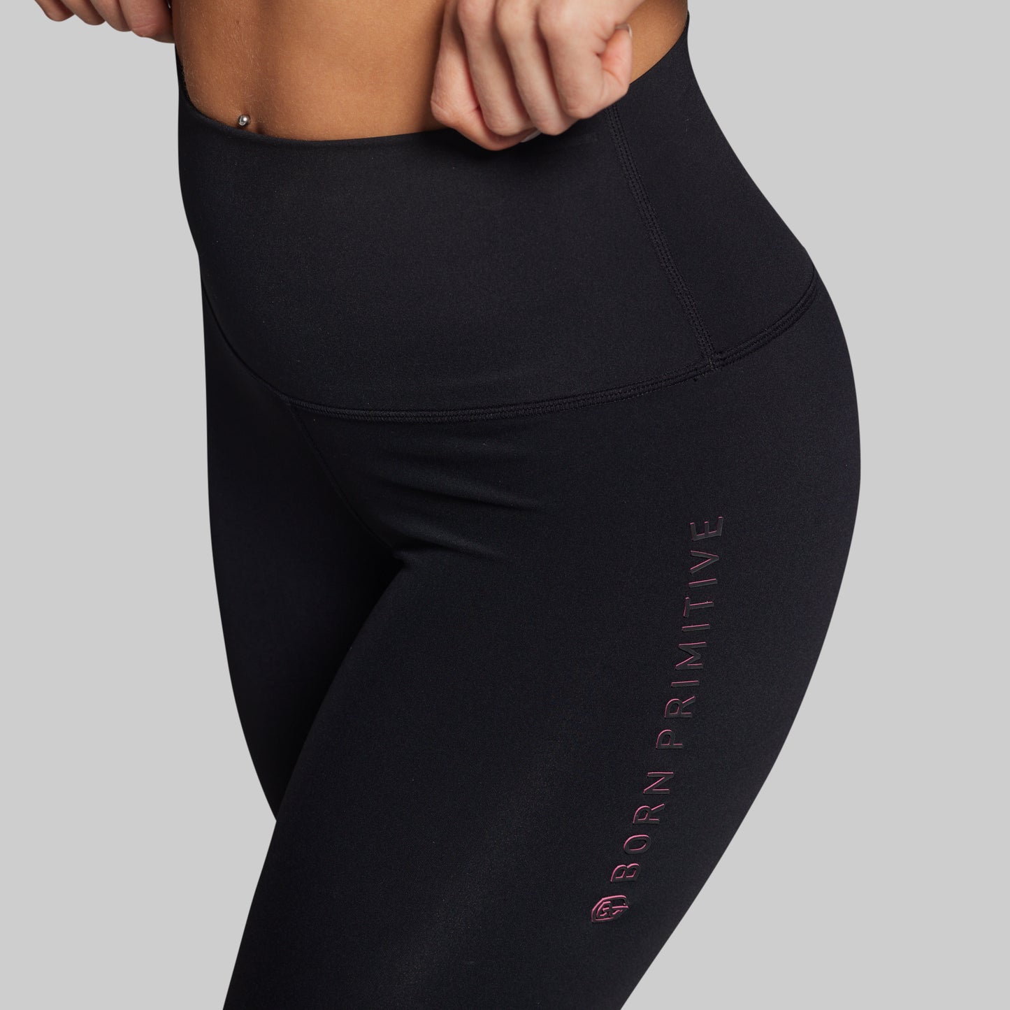 Black leggings with 'Born Primitive' branding on a gray background