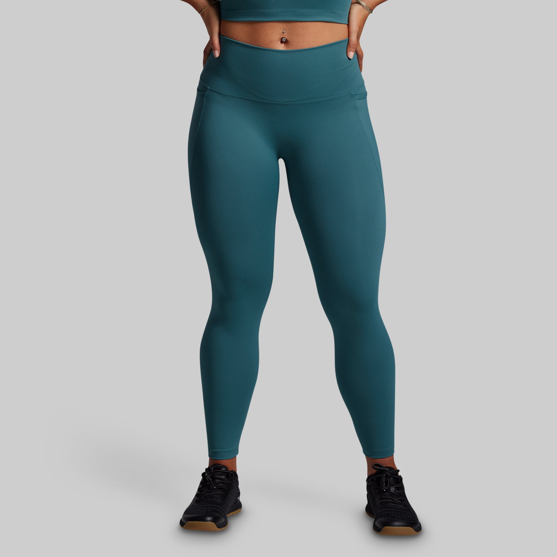 Teal leggings worn by a person on a gray background