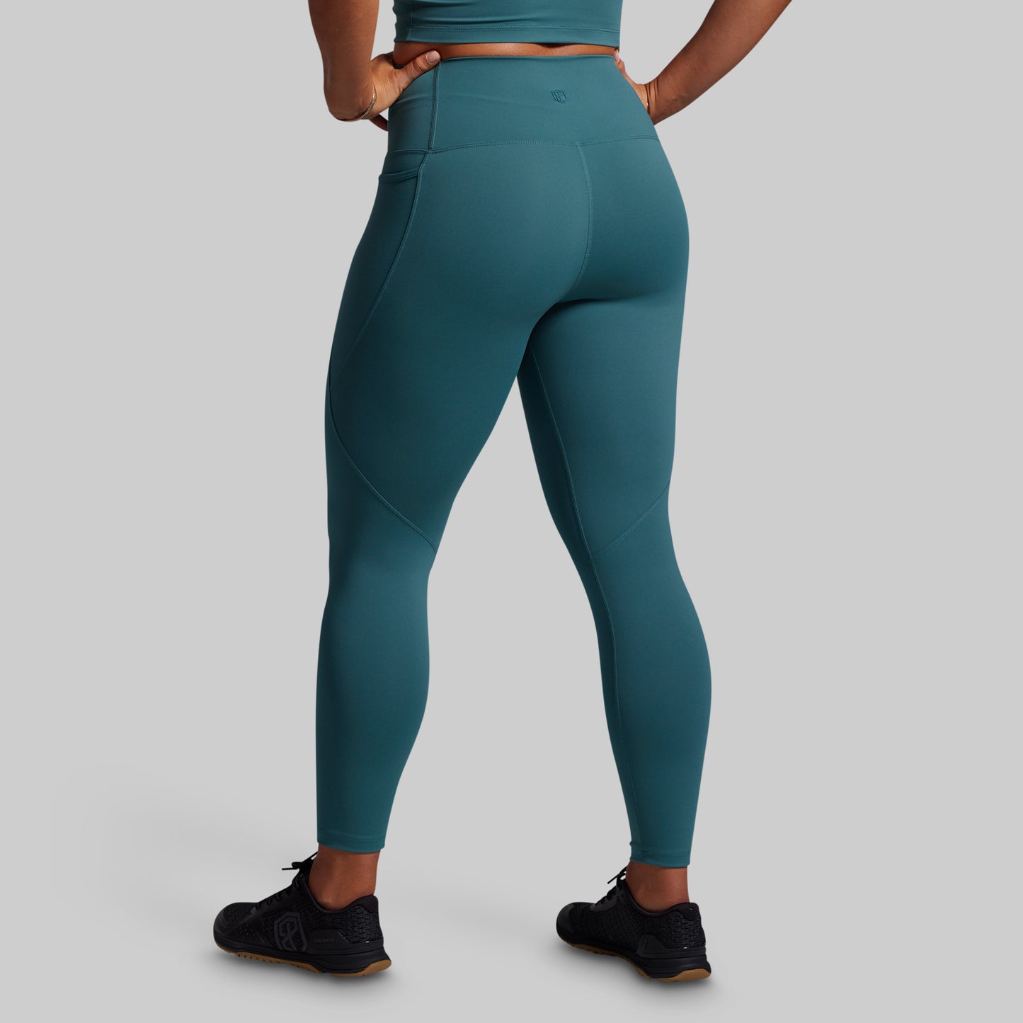Teal leggings worn by a person on a gray background