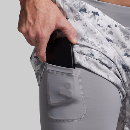 Person inserting a phone into a pocket of gray athletic pants with digital camouflage pattern.