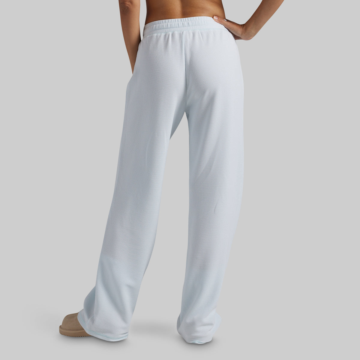 A person shown from the back wearing light blue wide-leg lounge pants against a plain light gray studio background.