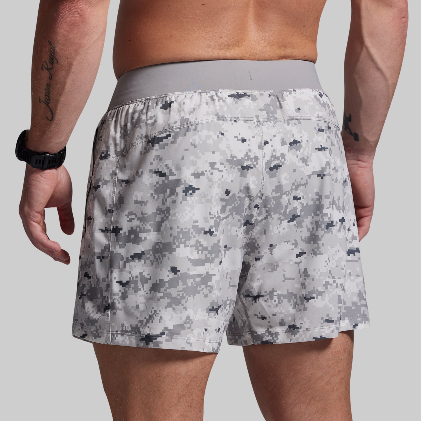 Person wearing camouflage shorts on a plain background