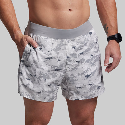 Person wearing camouflage shorts on a plain background