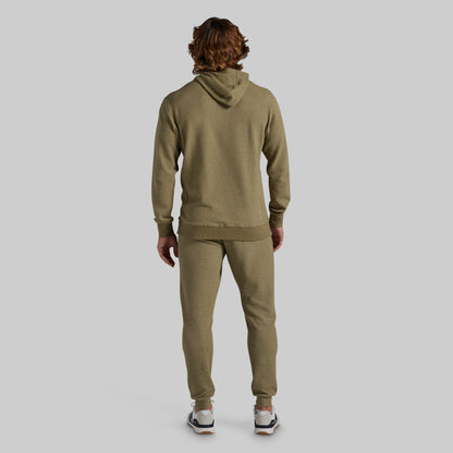 A man viewed from behind wearing a matching olive green hoodie and jogger sweatpants set, standing against a solid light gray background.