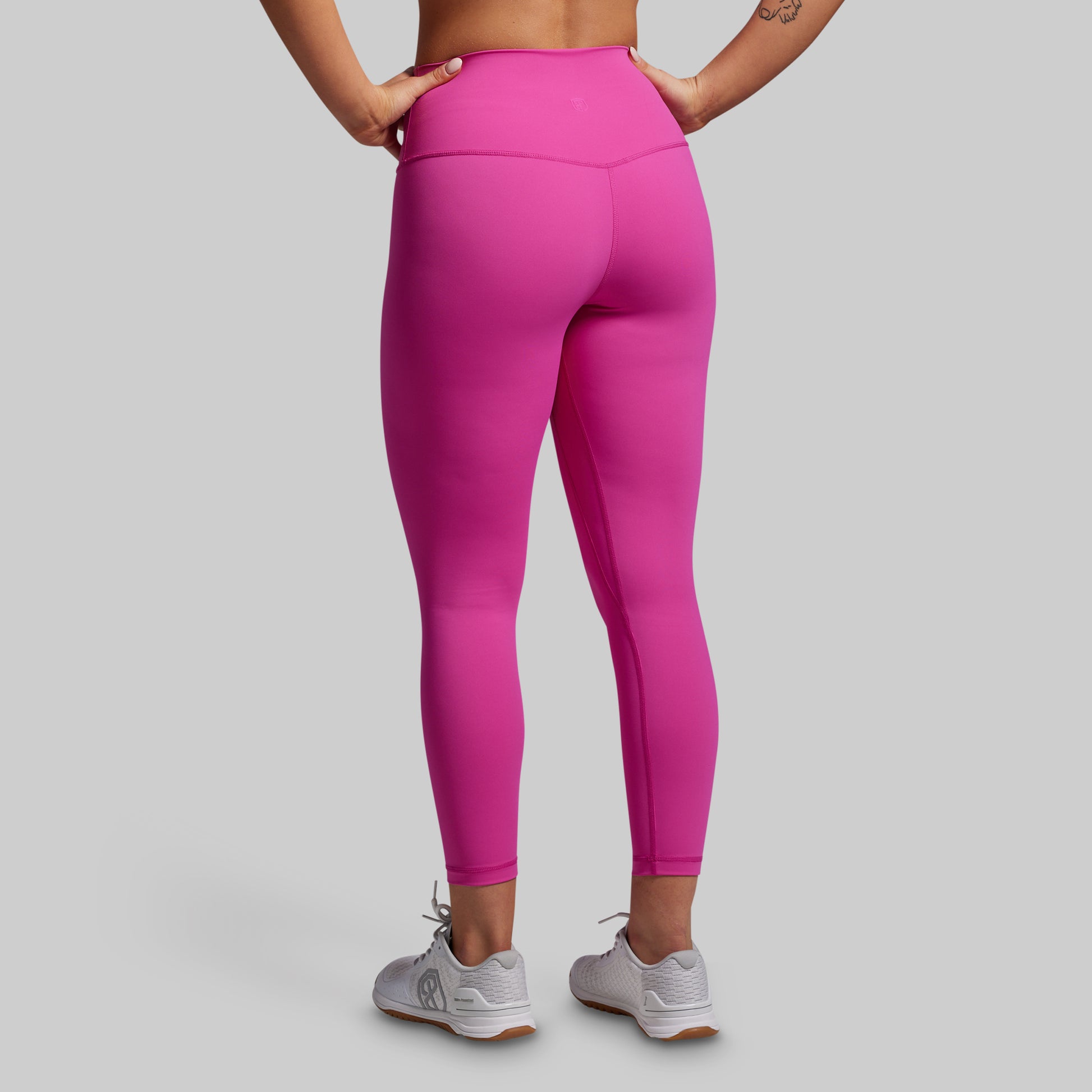 Person wearing bright pink leggings on a light gray background