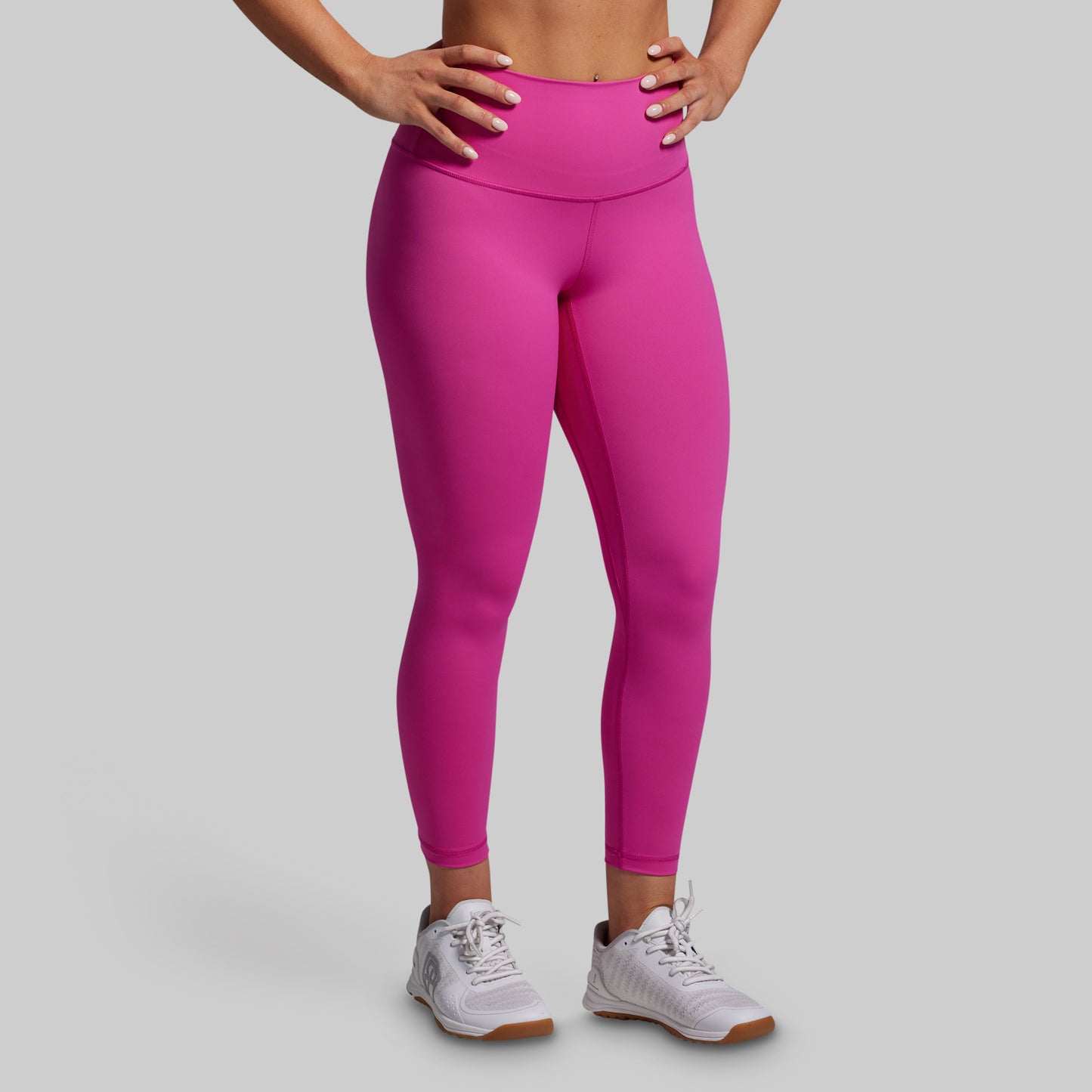 Person wearing bright pink leggings on a gray background