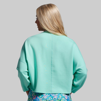 Person wearing a light blue jacket with a plain background