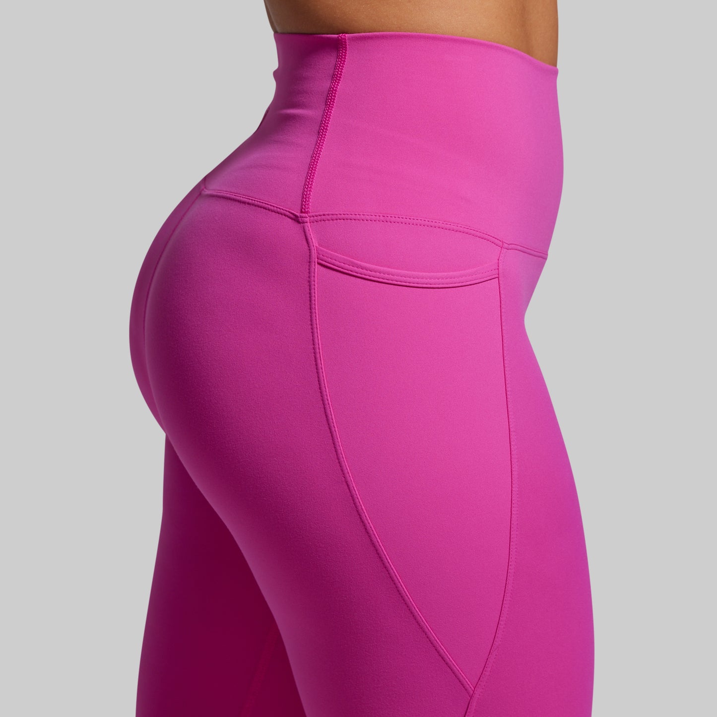 Close-up of the pocket of bright pink leggings on a gray background