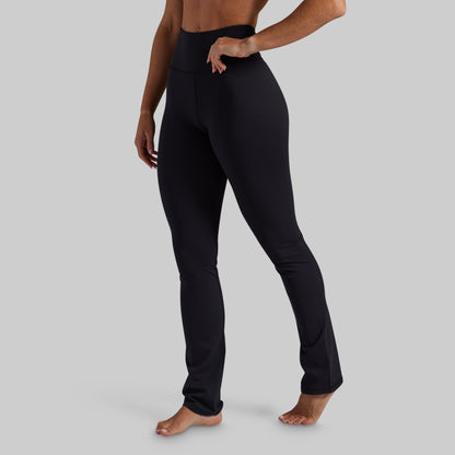 A model wearing black high-waisted yoga pants, shown from the waist down against a solid gray background.