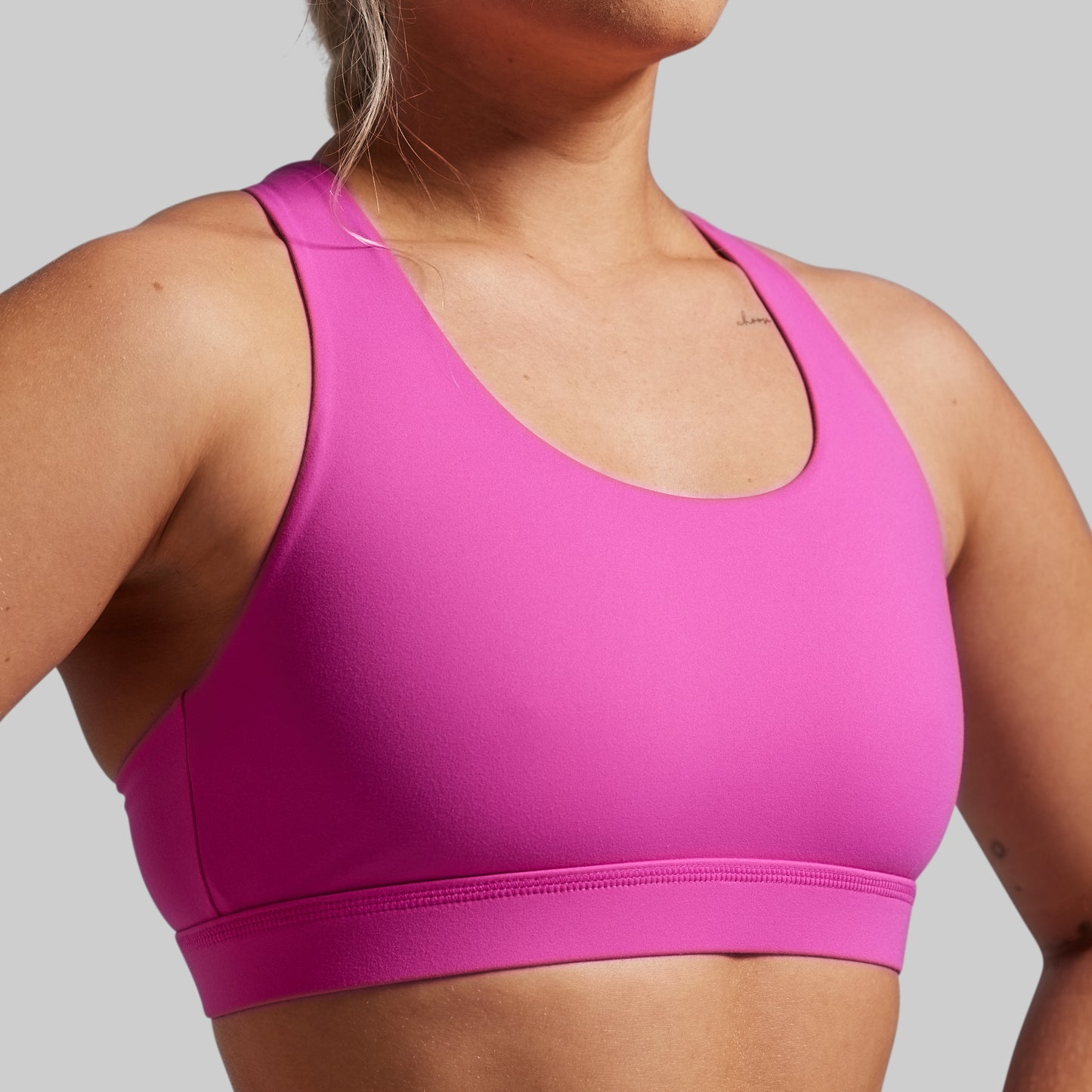 Pink sports bra worn by a person on a gray background