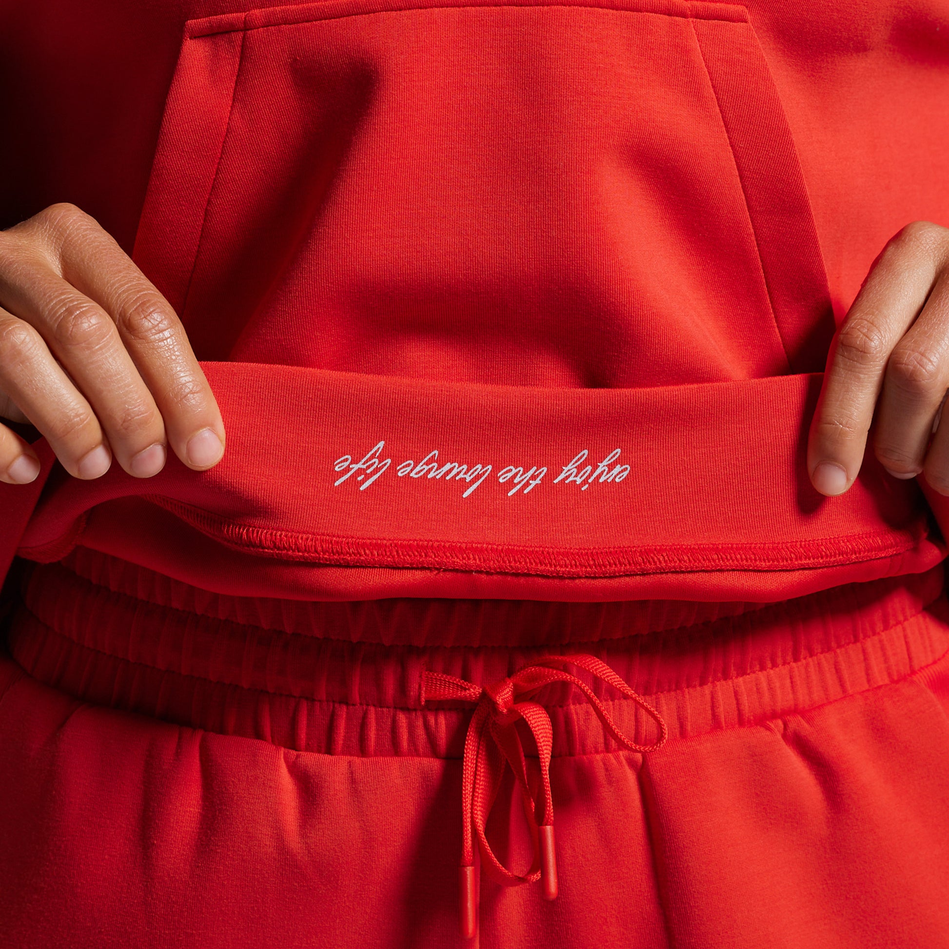 Red sweatshirt with text on the hem held by a person