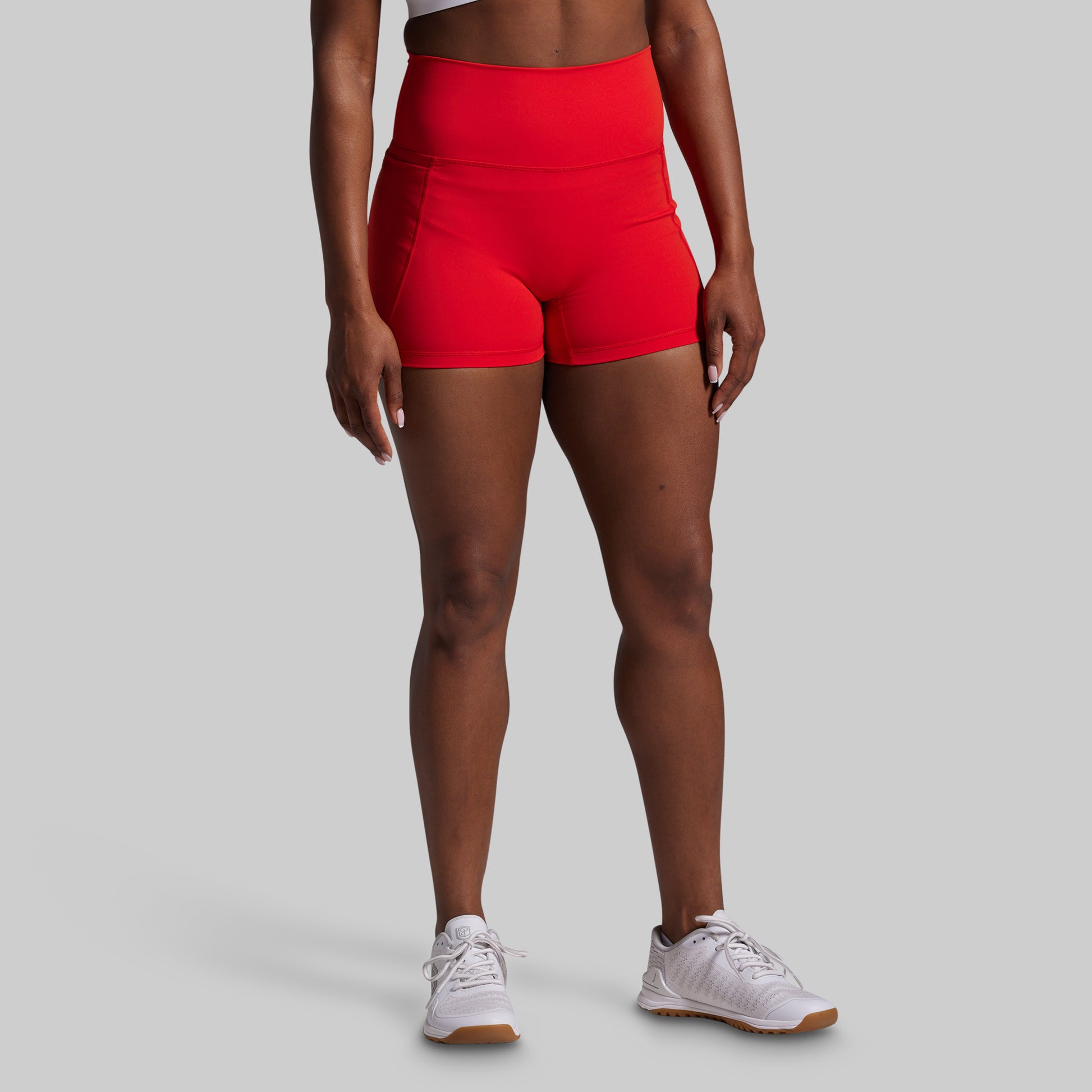 Person wearing red high-waisted shorts on a gray background