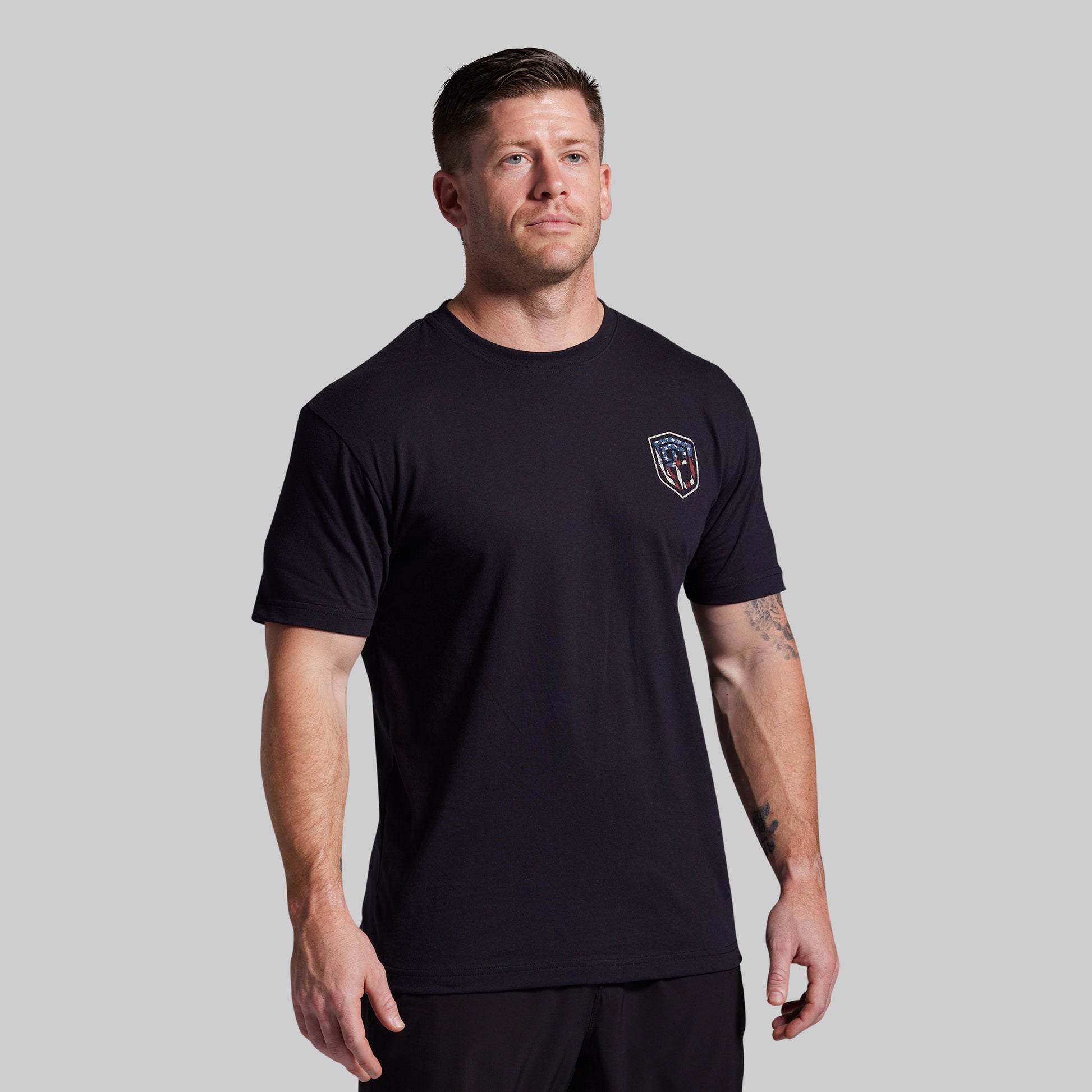 Man wearing a black t-shirt with a logo on a gray background