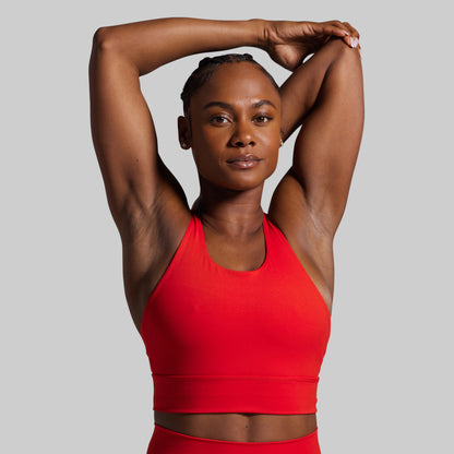 Woman wearing a red sports bra and shorts on a gray background