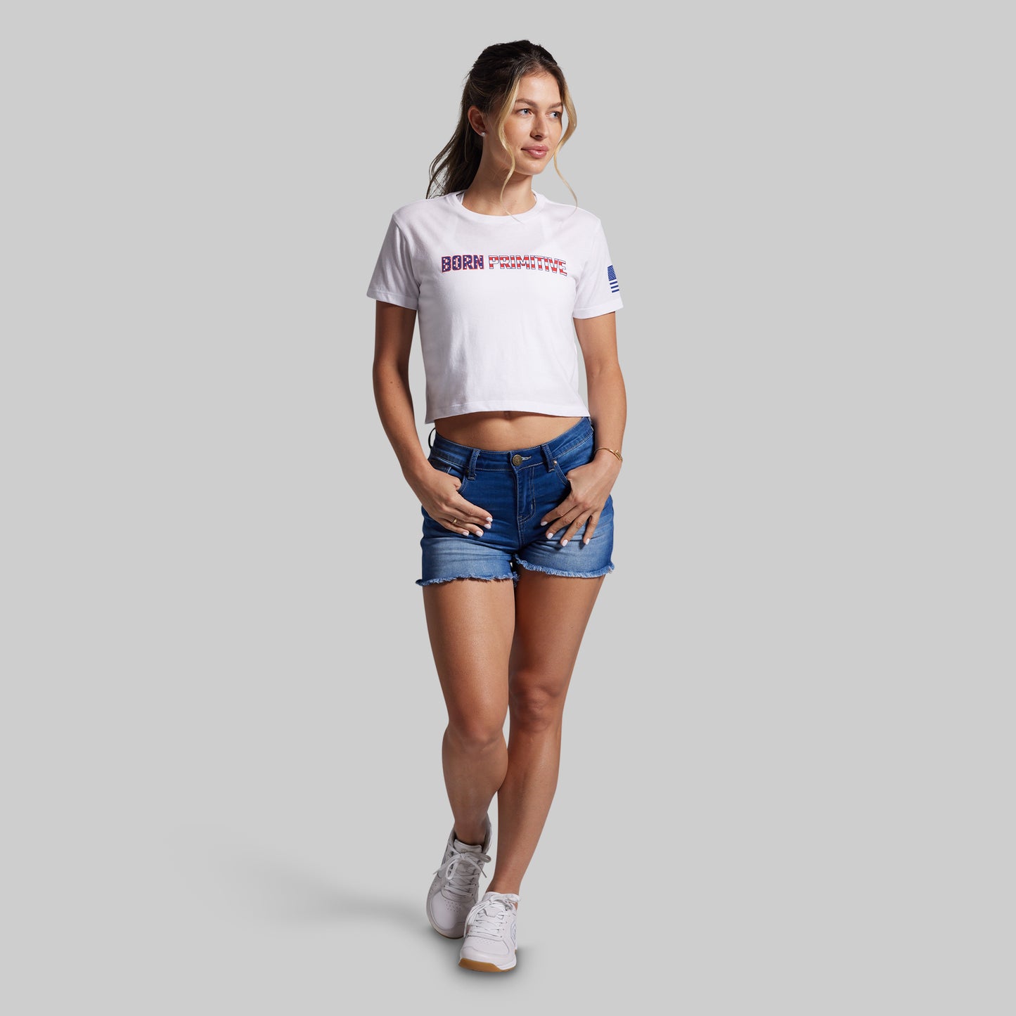 Woman wearing a white t-shirt with text and blue shorts on a gray background