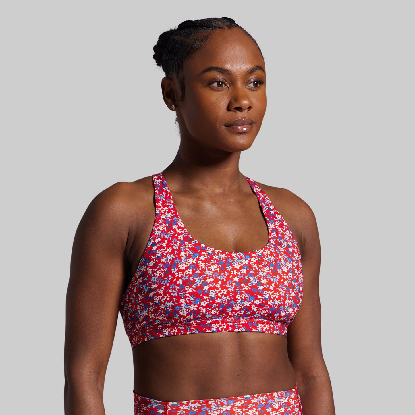Woman wearing a colorful sports bra and shorts on a gray background