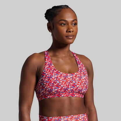 Woman wearing a colorful sports bra and shorts on a gray background