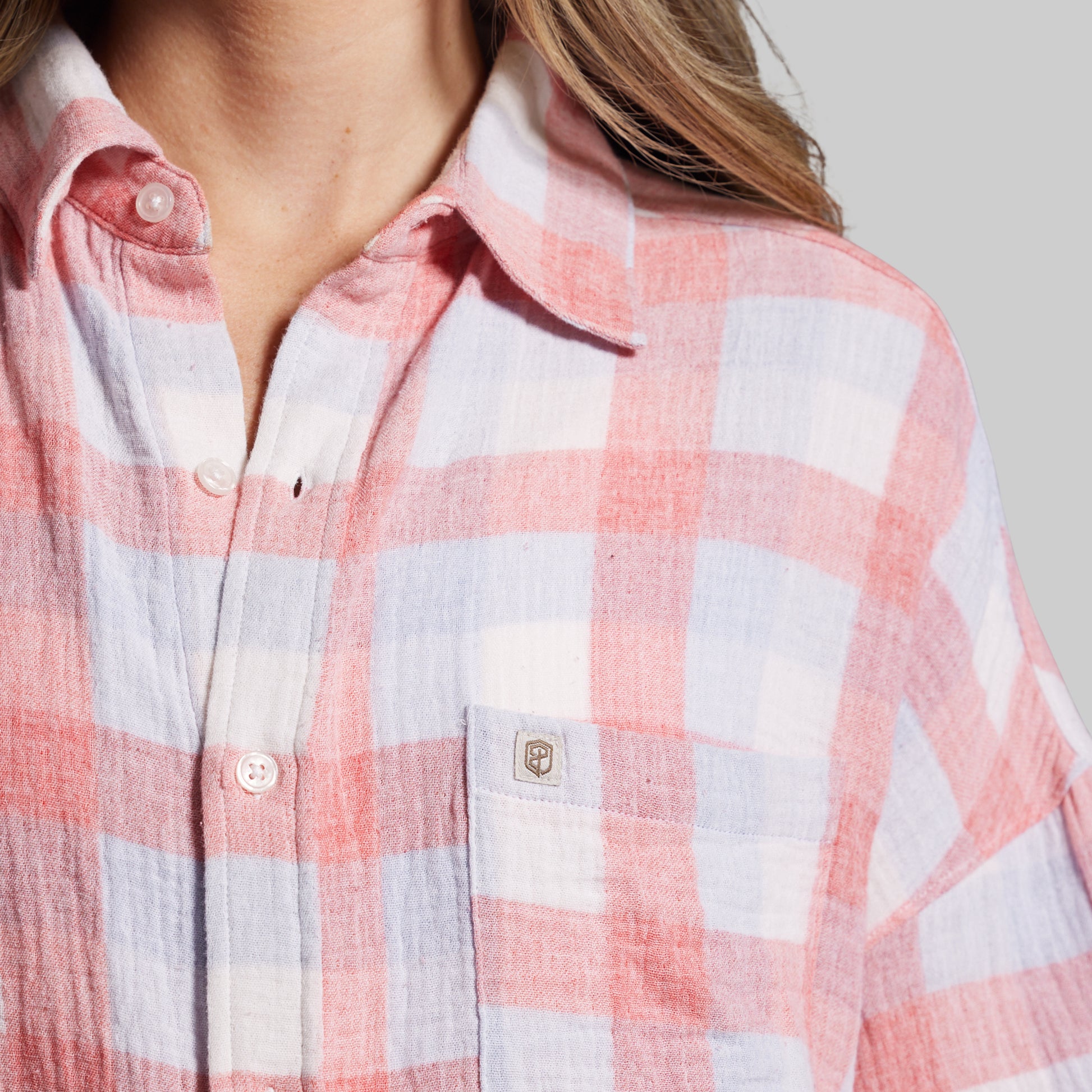 Close-up of a person wearing a pink and white checkered shirt.