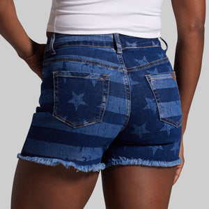 Blue denim shorts with star pattern worn by a person on a plain background