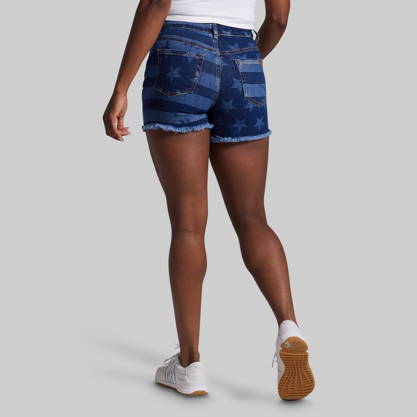 Person wearing blue denim shorts with American flag pattern on a gray background