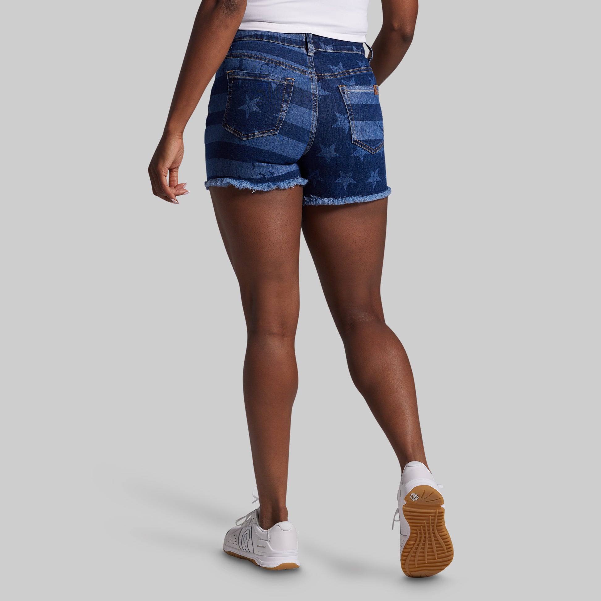 Person wearing blue denim shorts with American flag pattern on a gray background