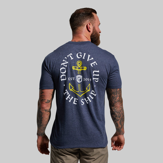 Man wearing a navy blue t-shirt with a yellow and white graphic design on the back, featuring text and an anchor symbol.