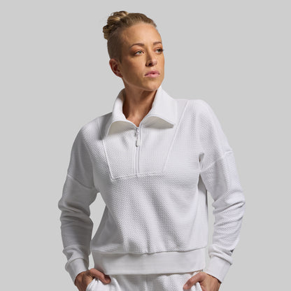 Woman wearing a white quarter-zip sweatshirt against a gray background